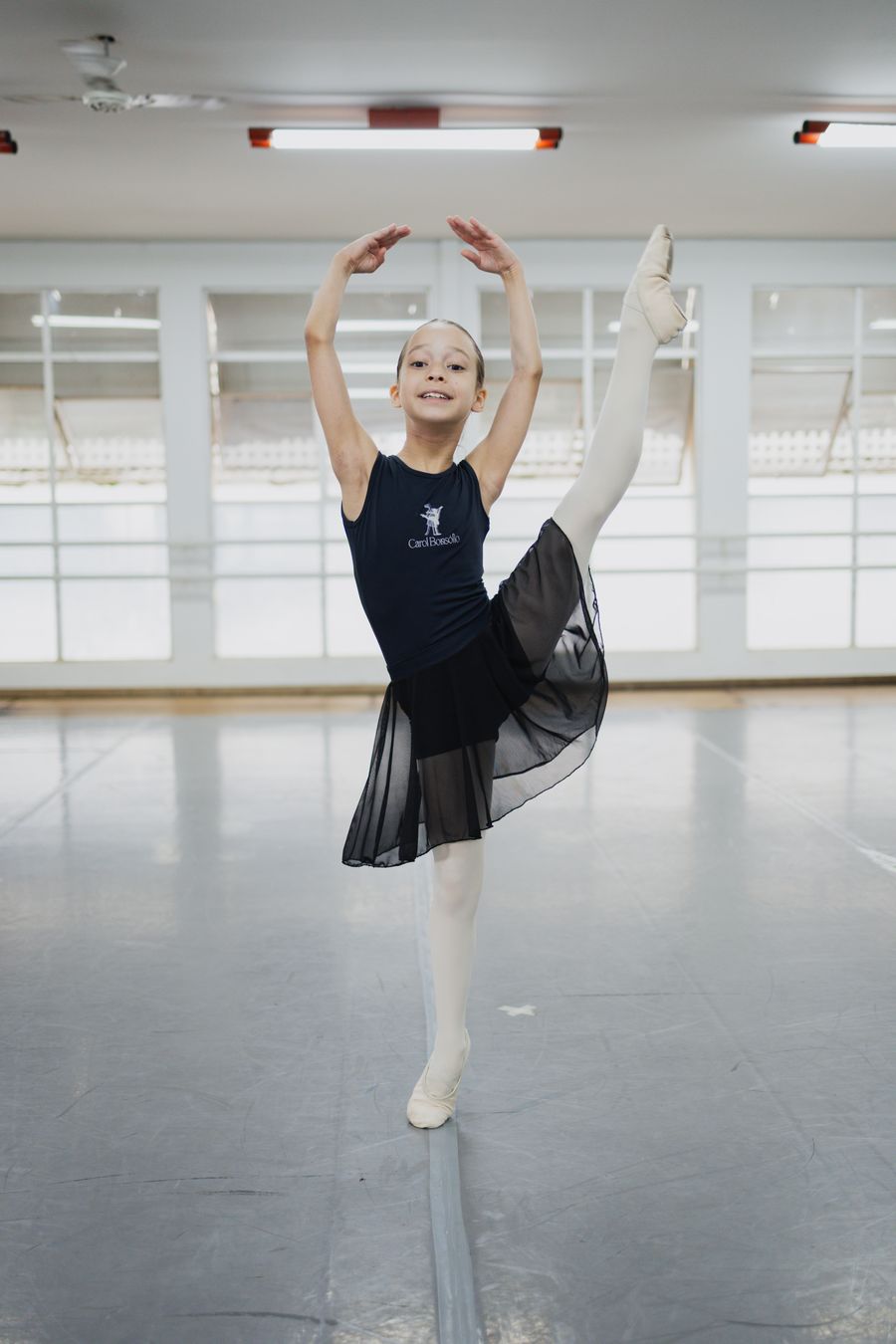 Aluna fazendo pose de ballet na sala da escola